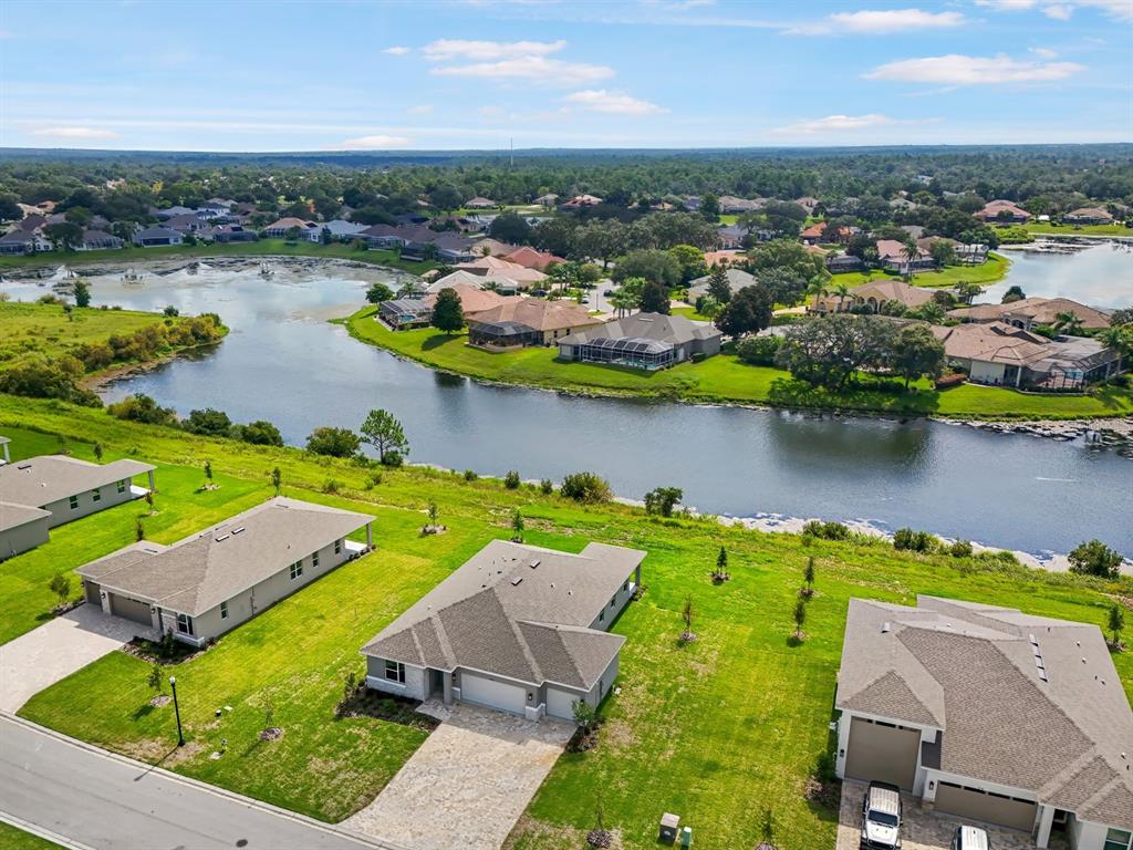 An aerial view shows several suburban houses with lawns situated along a large lake — 9156 PLAYERS DRIVE, WEEKI WACHEE, FL