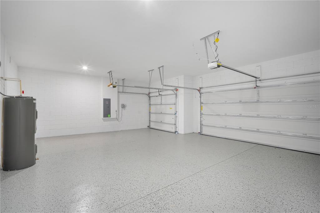 A clean, empty two-car garage with white block walls and a speckled epoxy floor — 9156 PLAYERS DRIVE, WEEKI WACHEE, FL