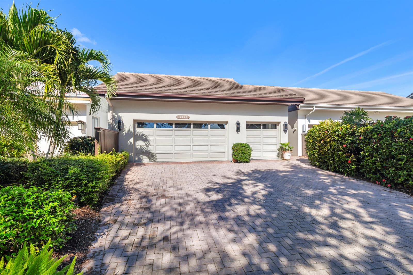 A house exterior features a two-car garage, a paved driveway, and lush landscaping — 12079 SE Birkdale Run, Jupiter FL 33469, JUPITER, FL