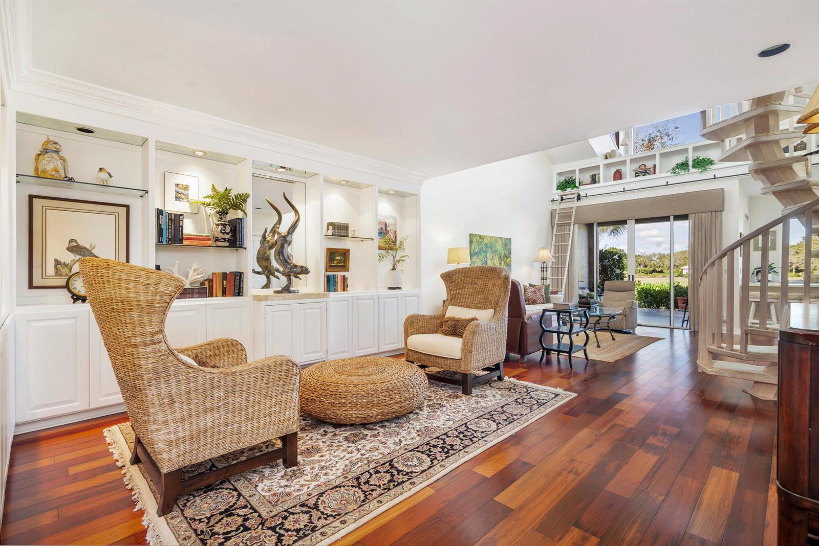A living room features built-in white shelving, wicker armchairs, a spiral staircase, and hardwood floors — 12079 SE Birkdale Run, Jupiter FL 33469, JUPITER, FL