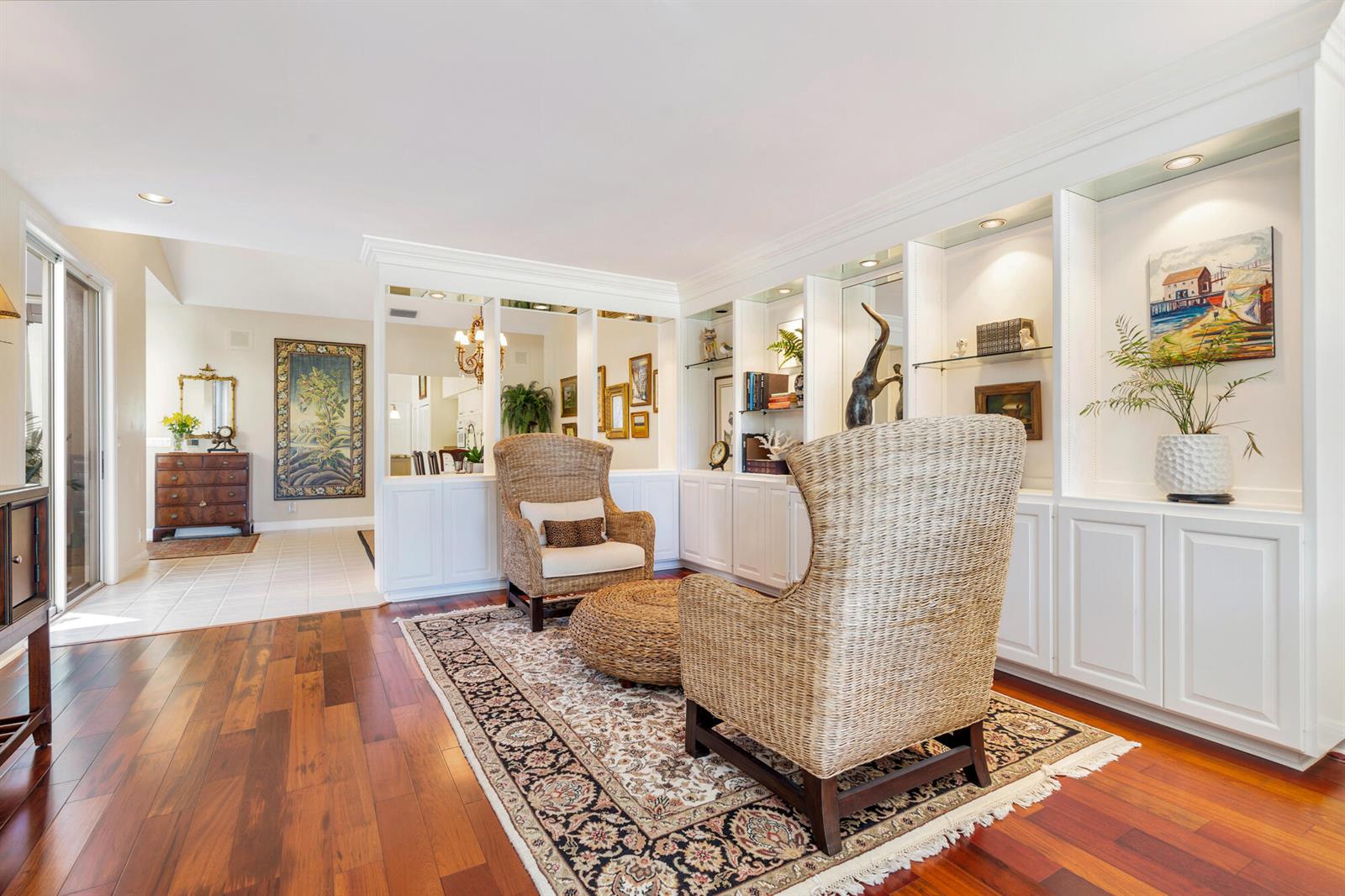 A living room features two wicker armchairs, a round ottoman, built-in shelving, and hardwood floors — 12079 SE Birkdale Run, Jupiter FL 33469, JUPITER, FL