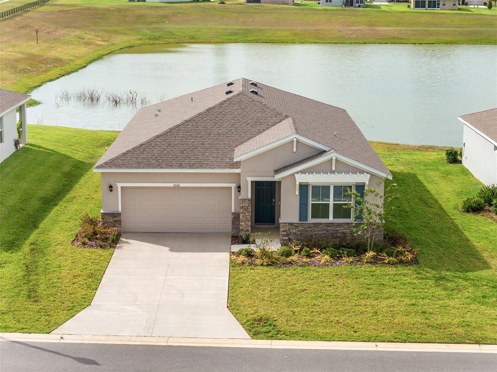 A screened-in patio with concrete flooring overlooks a grassy lawn and a small lake — 9358 SW 60TH TERRACE ROAD, OCALA, FL
