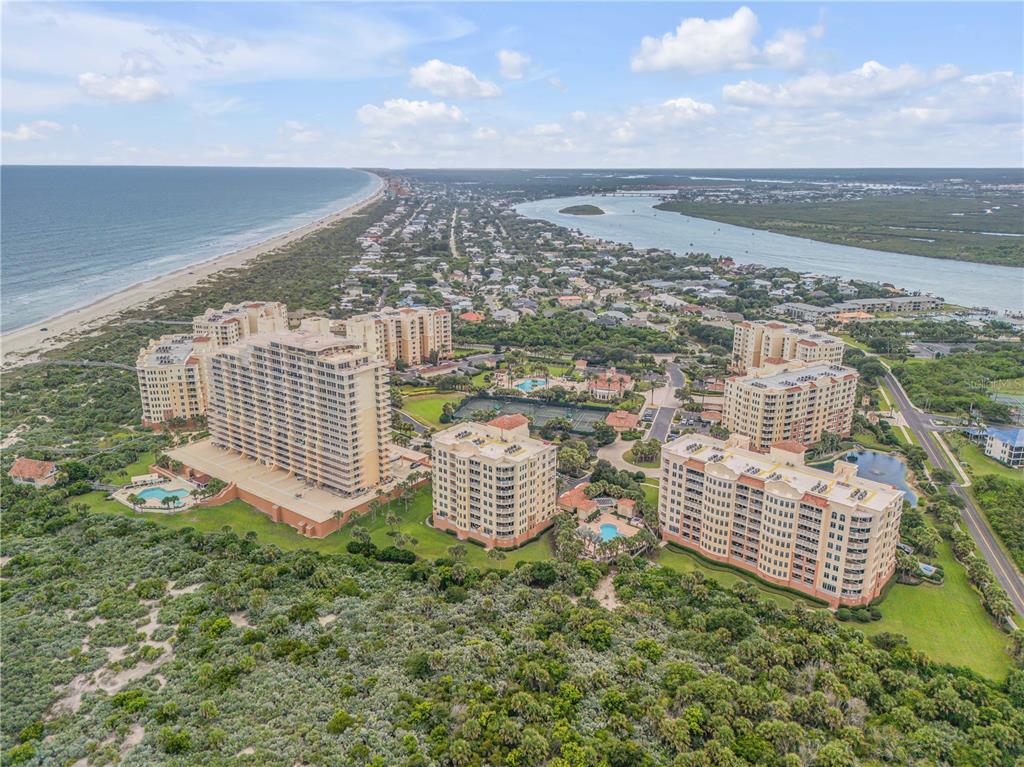 An aerial view shows high-rise residential buildings situated between the ocean and an inland waterway — 265 MINORCA BEACH WAY UNIT 404, NEW SMYRNA BEACH, FL