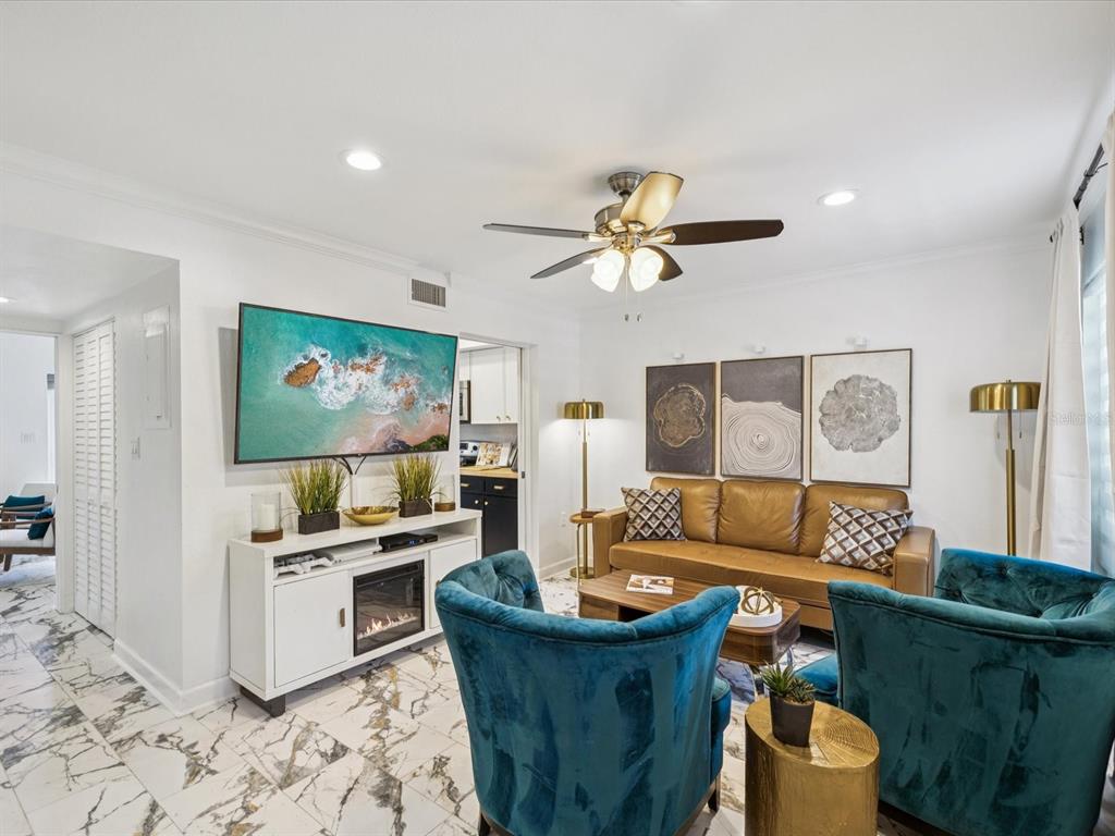 A living room features a tan leather sofa, two teal armchairs, and white marble flooring — 1308 70TH STREET N, ST PETERSBURG, FL