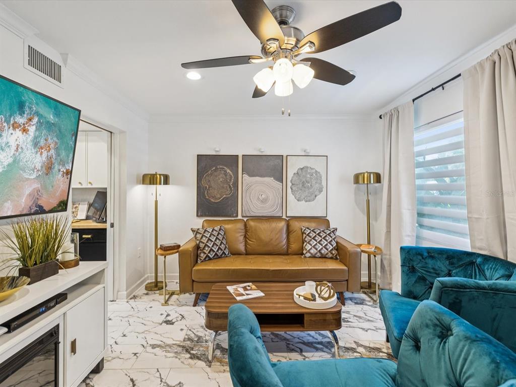 A living room features a brown leather sofa, teal velvet chairs, and white marble flooring — 1308 70TH STREET N, ST PETERSBURG, FL