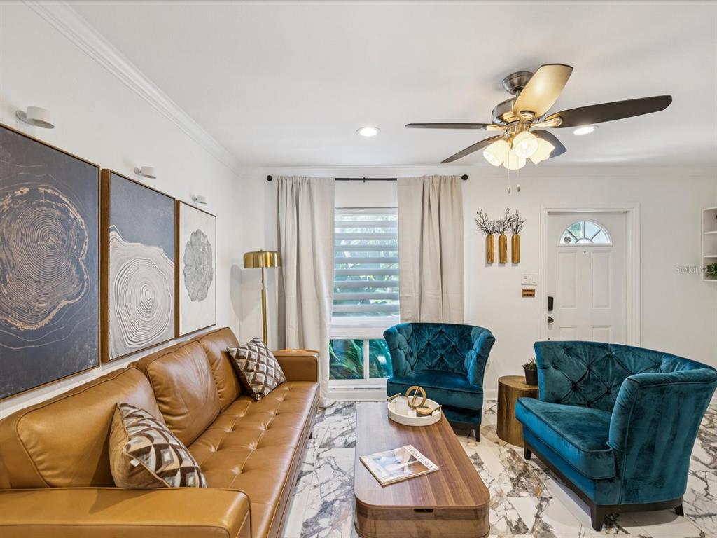 A living room features a tan leather sofa, two teal velvet chairs, and marble flooring — 1308 70TH STREET N, ST PETERSBURG, FL