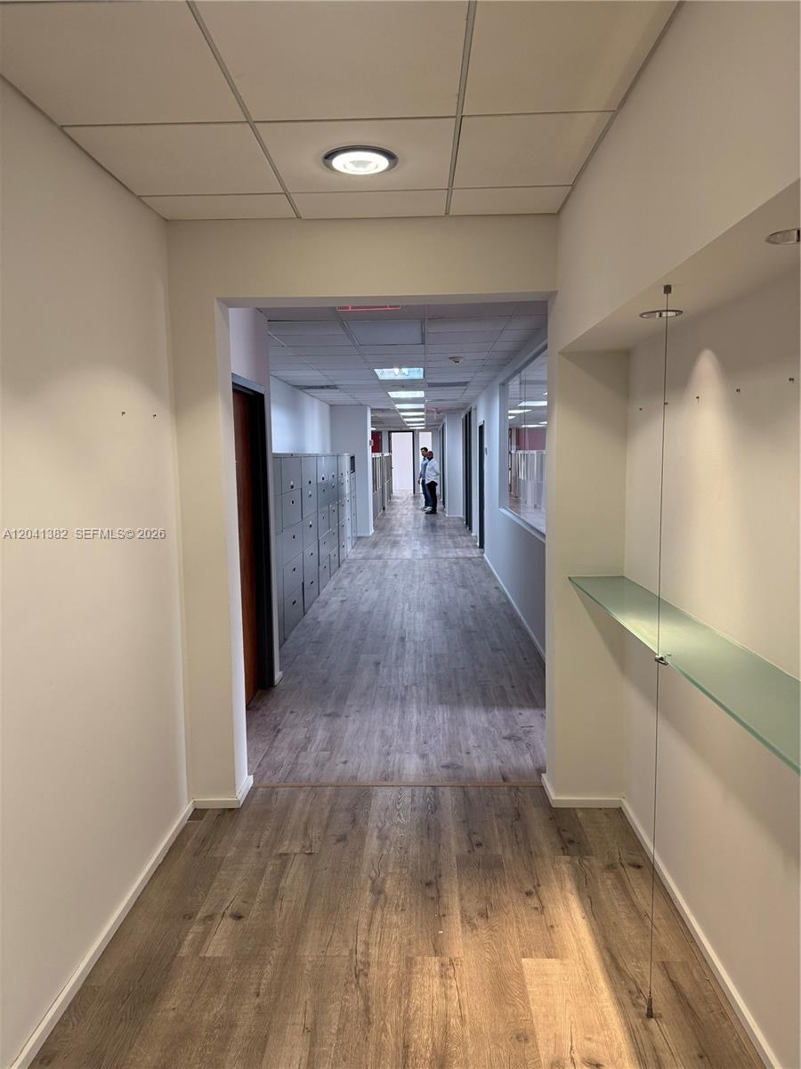 A long office hallway features wood-look flooring, recessed lighting, and a row of metal lockers — 8700 W Flagler St # 200, Miami FL 33174, MIAMI, FL