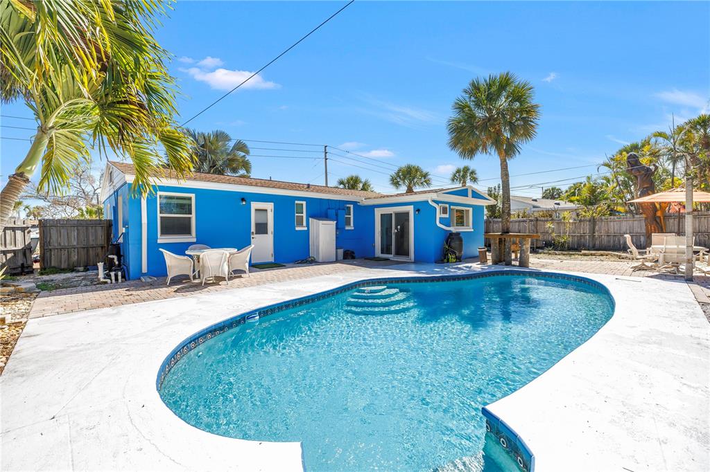 A bright blue house features a backyard swimming pool and a paved patio area — 6892 GULF WINDS DRIVE UNIT 1, ST PETE BEACH, FL