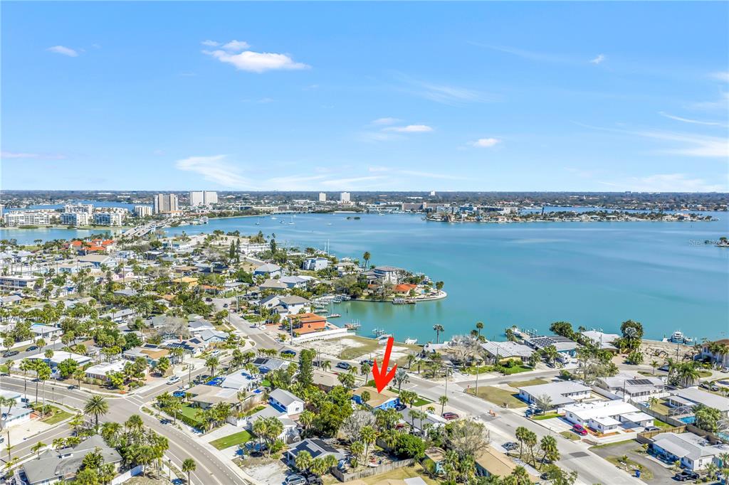 An aerial view shows a residential neighborhood near a bay with a red arrow pointing toward a house — 6892 GULF WINDS DRIVE UNIT 1, ST PETE BEACH, FL