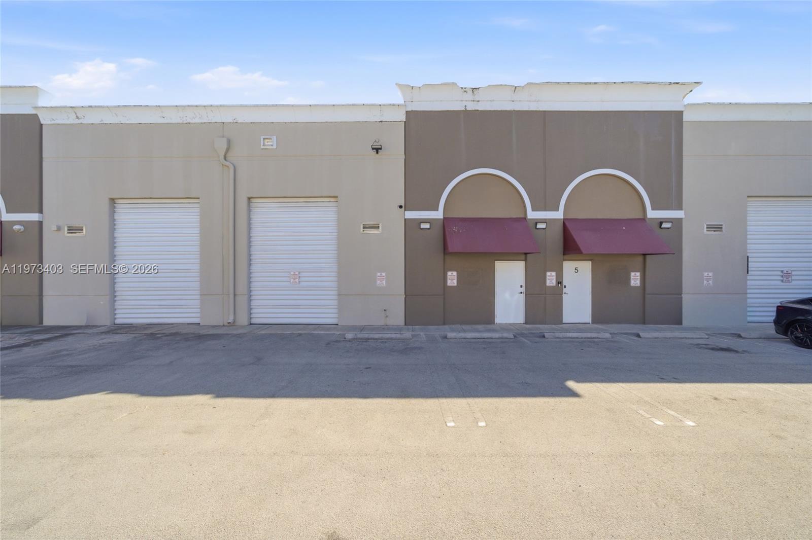 The exterior view shows a commercial building with roll-up garage doors and two entry doors — 13500 SW 134th Ave # 4A, Miami FL 33186, MIAMI, FL