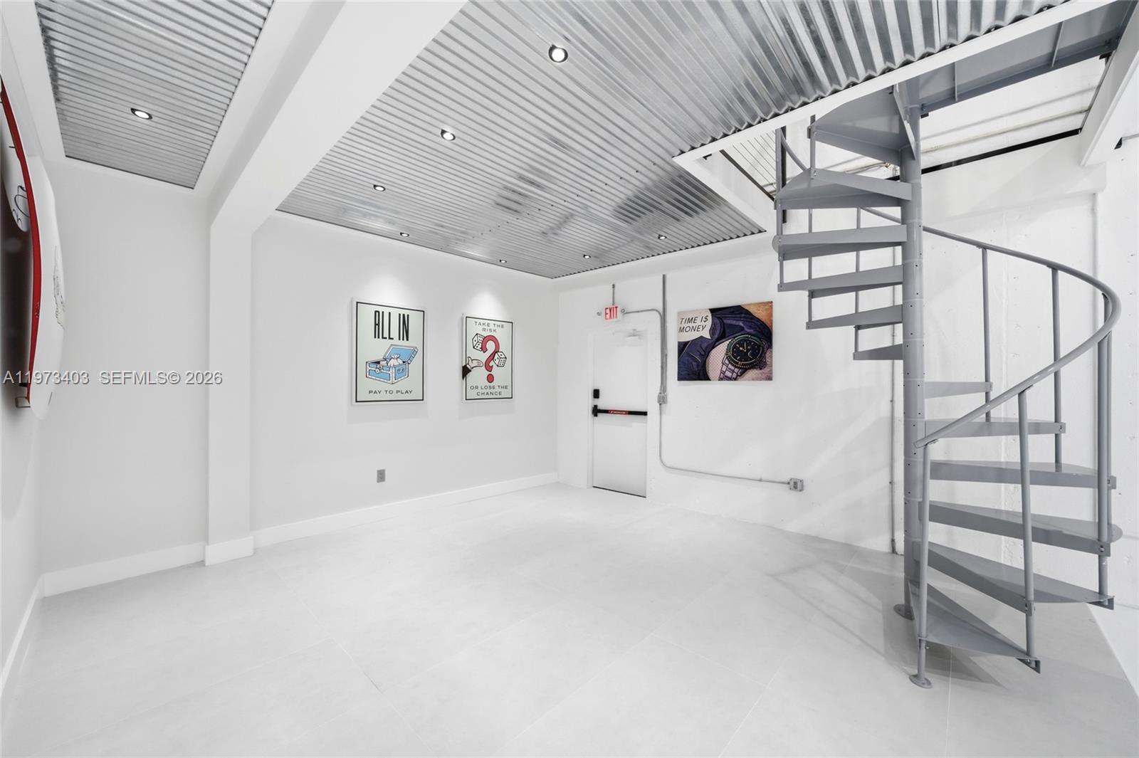 A minimalist room features a corrugated metal ceiling, white tile floors, and a spiral staircase — 13500 SW 134th Ave # 4A, Miami FL 33186, MIAMI, FL