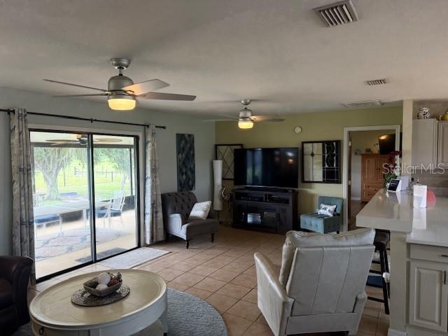 A living room features tile flooring, two ceiling fans, a television, and sliding glass doors — 5015 TWIN LAKES LANE, BARTOW, FL