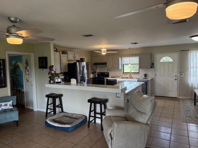 An open-concept kitchen with a breakfast bar overlooks a living area with tile flooring — 5015 TWIN LAKES LANE, BARTOW, FL