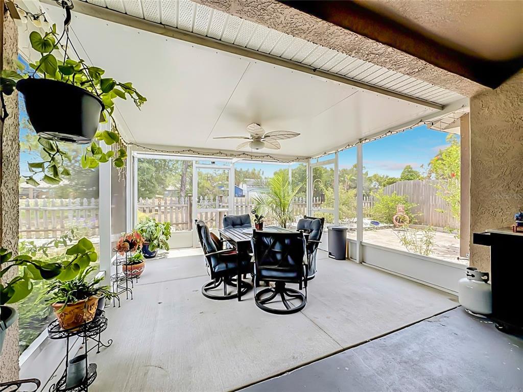 A screened-in patio features a dining set, ceiling fan, and potted plants on concrete flooring — 6630 CAMBRIDGE PARK DRIVE, APOLLO BEACH, FL