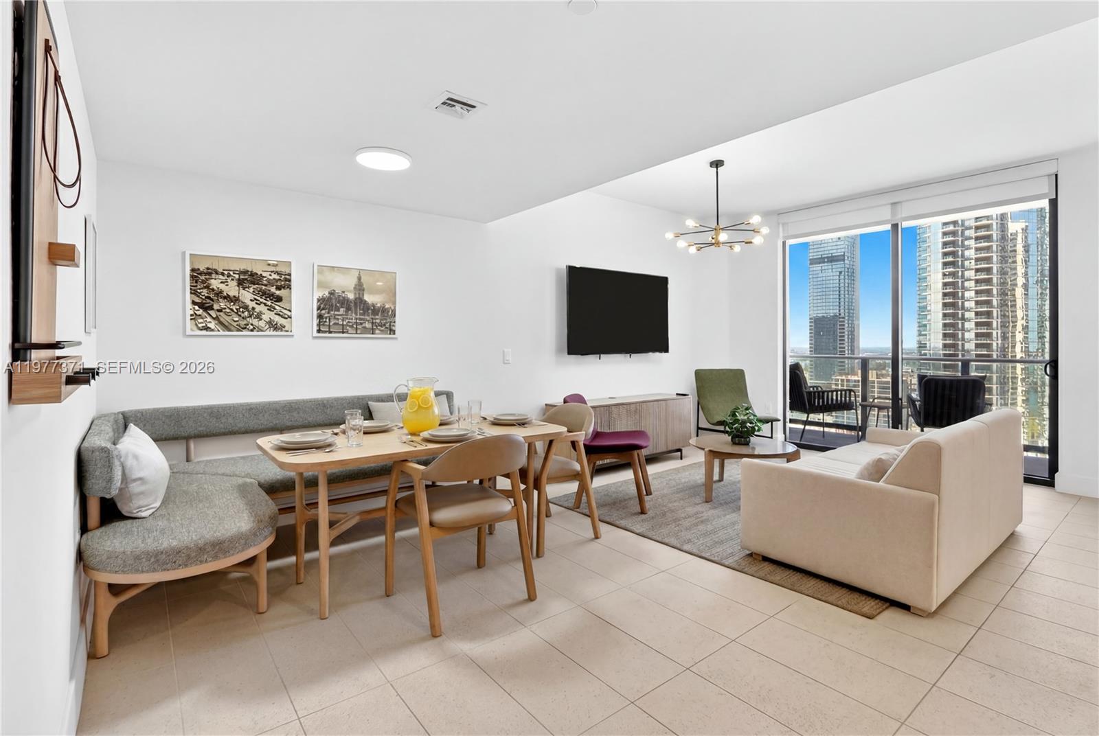 An open-concept living and dining area features a banquette, modern furniture, and floor-to-ceiling windows — 159 NE 6th St # 2711, Miami FL 33132, MIAMI, FL