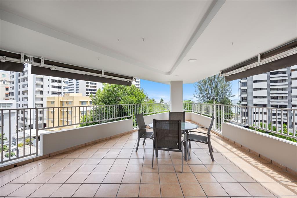 A spacious, tiled balcony features a dining set under a covered roof with metal railings — 1520 ASHFORD AVE UNIT 4, SAN JUAN, PR