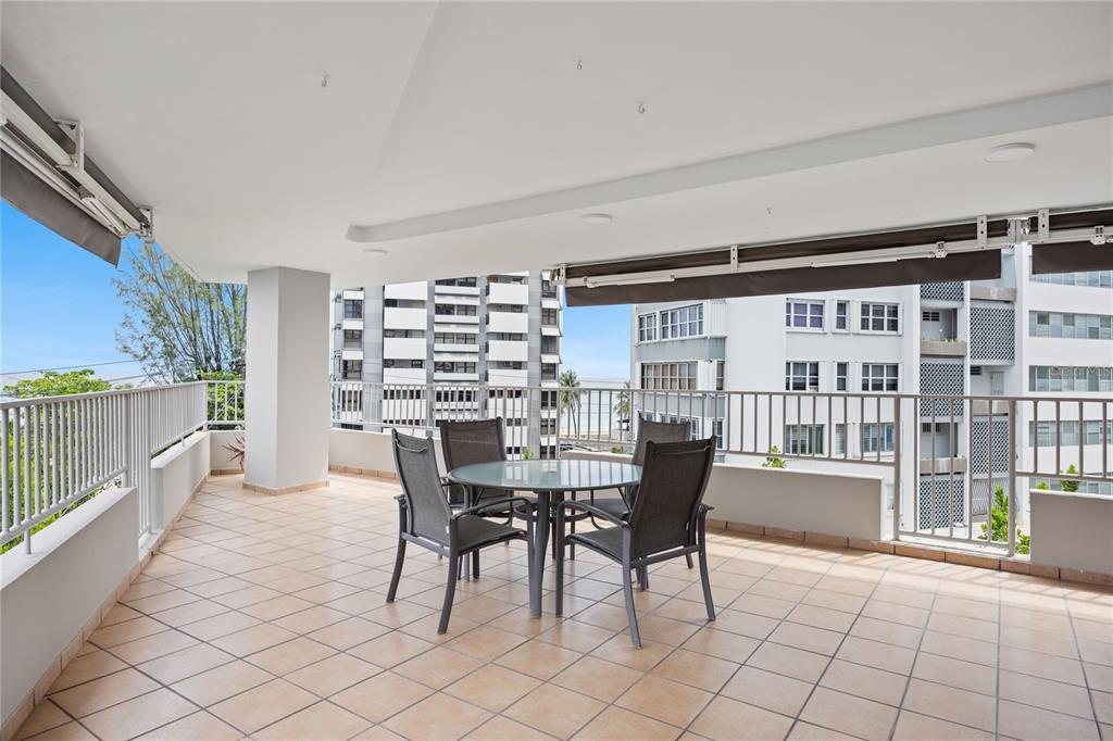 A spacious covered balcony features a glass-top dining table with four chairs and tiled flooring — 1520 ASHFORD AVE UNIT 4, SAN JUAN, PR