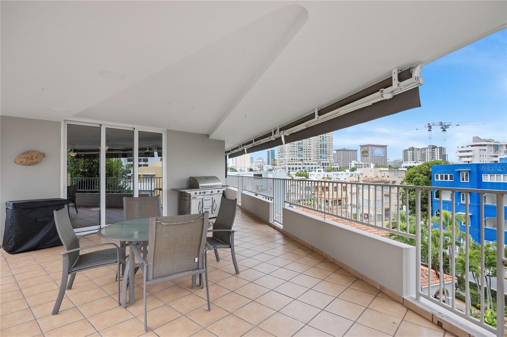 A balcony with tile flooring, outdoor dining furniture, a grill, and a view of city buildings — 1520 ASHFORD AVE UNIT 4, SAN JUAN, PR