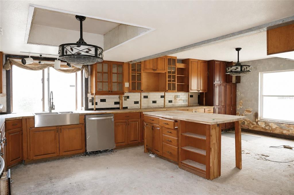 An unfinished kitchen features wood cabinets, a stainless steel sink, and a central island — 419 ALLSPICE COURT, KISSIMMEE, FL