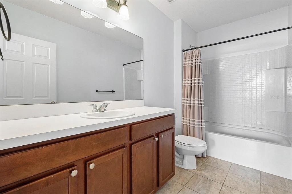 A bathroom features a wooden vanity, a large mirror, and a shower-tub combination — 119 SW 2ND AVENUE, BOYNTON BEACH, FL