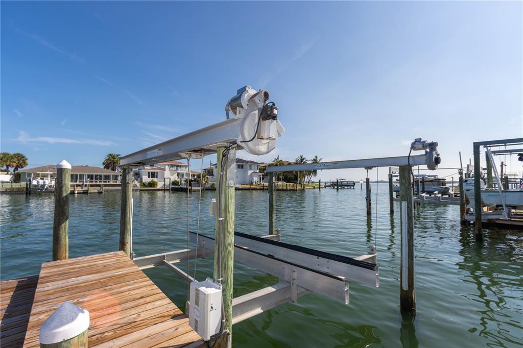 A boat lift with metal beams and motors sits over the water at a wooden dock — 440 PALM ISLAND SE, CLEARWATER BEACH, FL