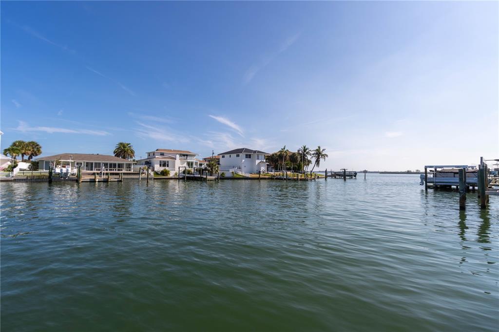 A view of waterfront houses with private docks along a canal under a clear sky — 440 PALM ISLAND SE, CLEARWATER BEACH, FL