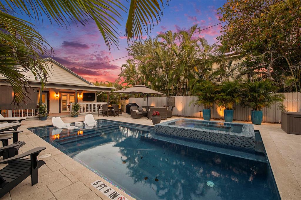 A backyard patio features a swimming pool with an attached spa and outdoor lounge furniture — 135 93RD AVENUE, TREASURE ISLAND, FL