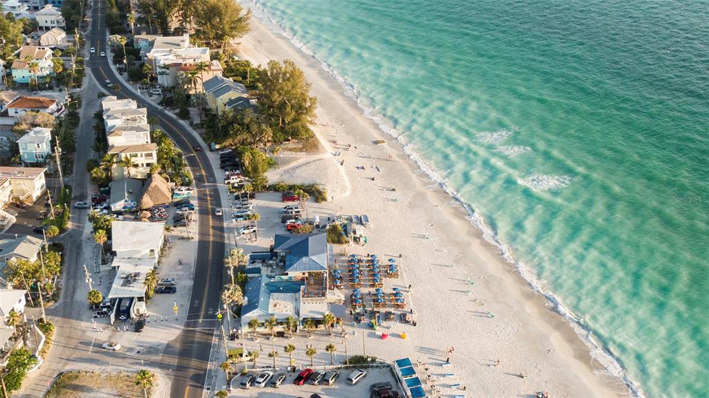 An aerial view shows a coastal road, beach parking, a restaurant, and the ocean — 135 93RD AVENUE, TREASURE ISLAND, FL