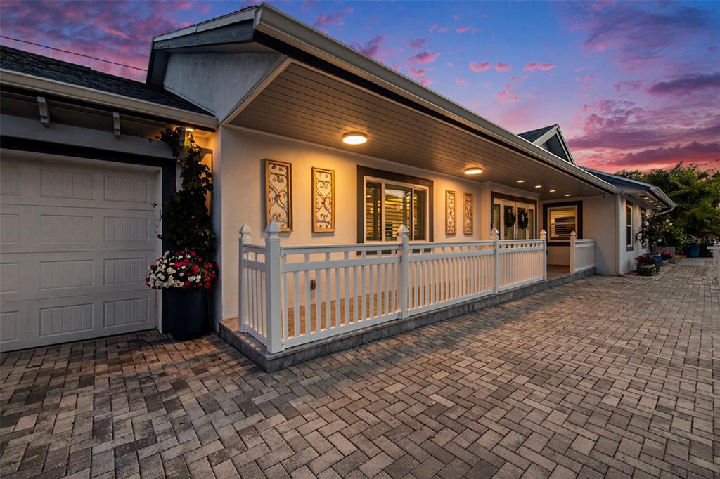 A white house with a paved driveway, a white picket fence, and a garage at dusk — 135 93RD AVENUE, TREASURE ISLAND, FL