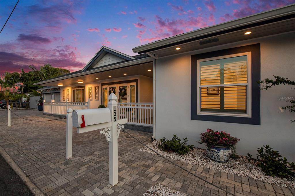 A white house with a brick driveway, a mailbox, and a covered porch at sunset — 135 93RD AVENUE, TREASURE ISLAND, FL