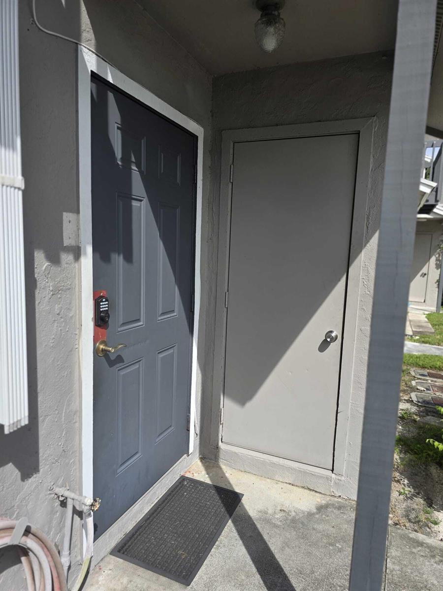An exterior view of a gray front door and an adjacent storage closet door — 5204 Bayside Drive # 5204, FL 33463, FL