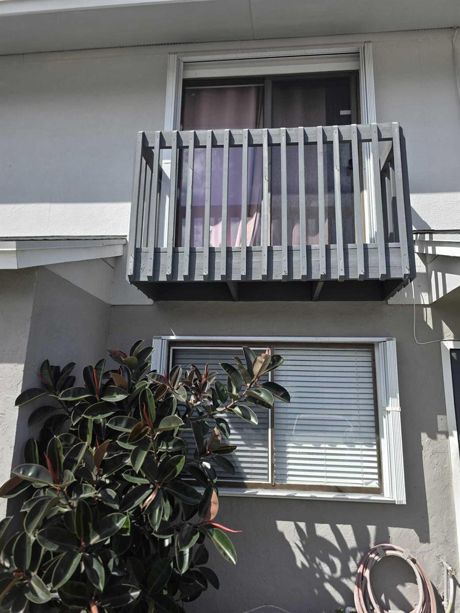 A two-story building exterior featuring a wooden balcony above a window and a large plant — 5204 Bayside Drive # 5204, FL 33463, FL