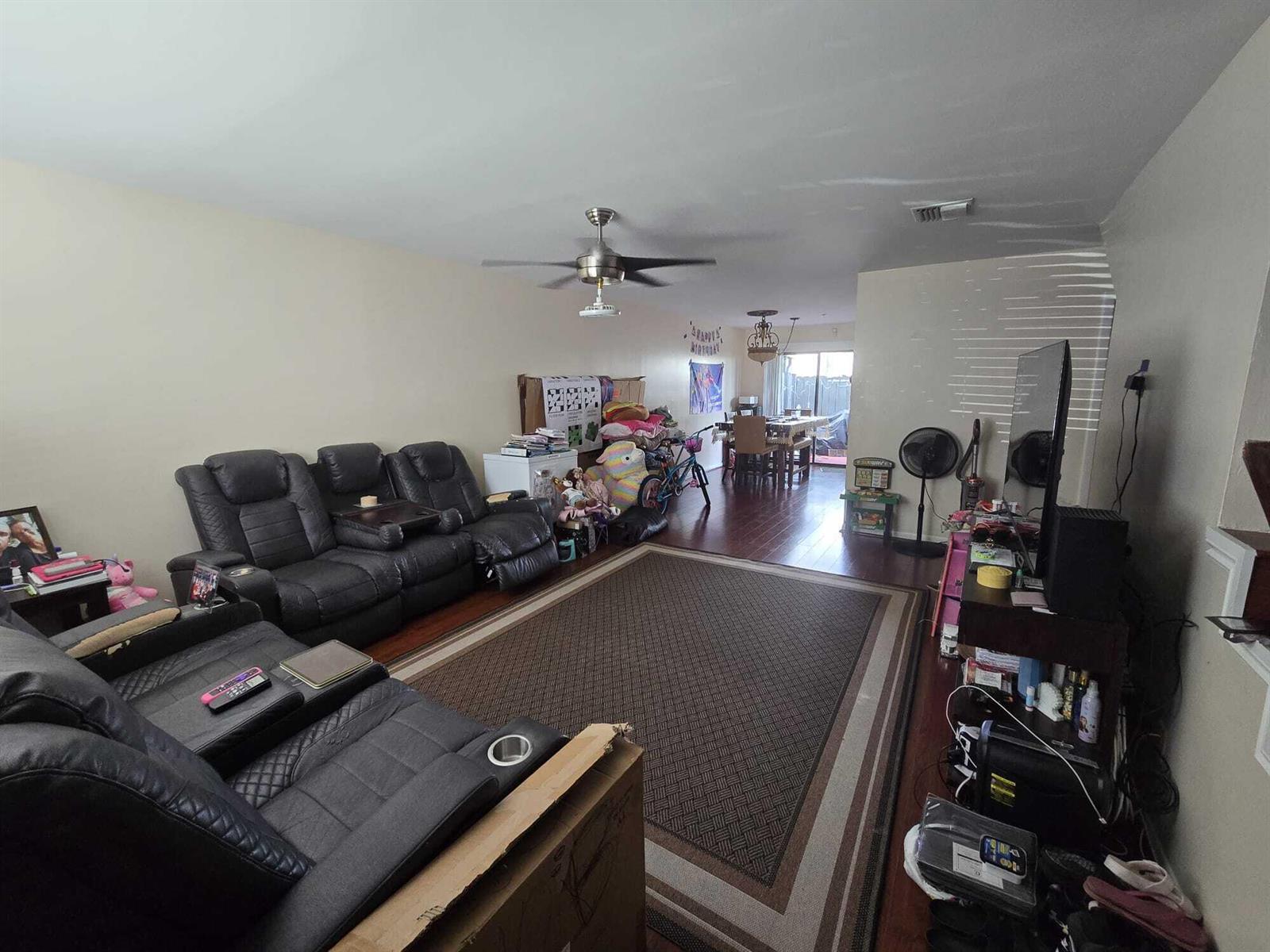 A living room with dark leather reclining sofas, a large area rug, and hardwood floors — 5204 Bayside Drive # 5204, FL 33463, FL