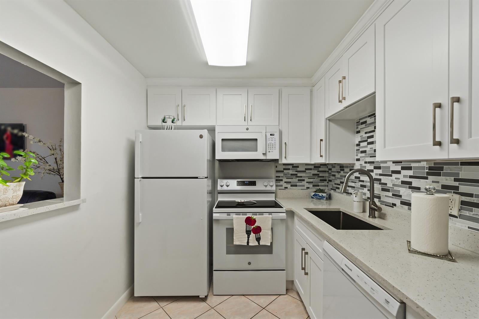 A kitchen with white cabinets, stainless steel appliances, a tiled backsplash, and light countertops — 126 Southampton B, West Palm Beach FL 33417, WEST PALM BEACH, FL