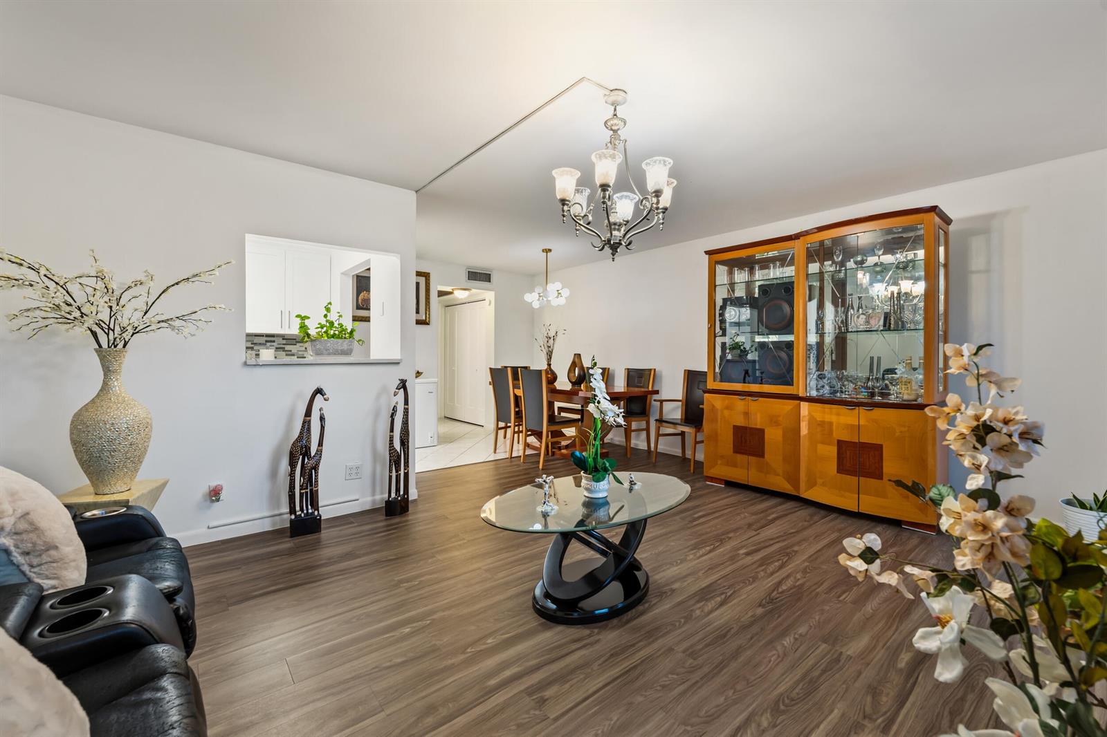 A living room with wood-look flooring, a glass coffee table, and a wooden china cabinet — 126 Southampton B, West Palm Beach FL 33417, WEST PALM BEACH, FL