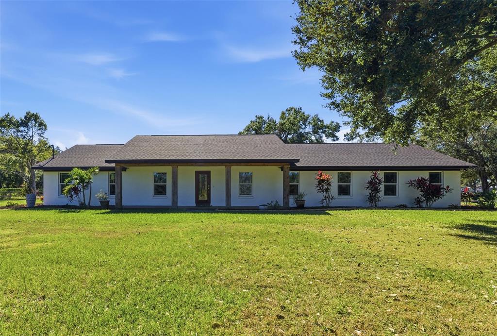A single-story white house with a dark roof and wooden porch pillars sits on grass — 2506 HAWK GRIFFIN ROAD, PLANT CITY, FL