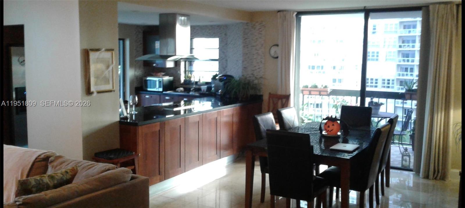 A patio with lounge chairs and a dining set overlooks a calm body of water — 2333 Brickell Ave # 602, Miami FL 33129, MIAMI, FL