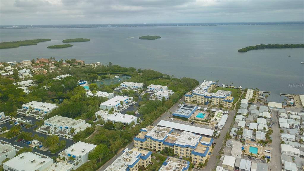 An aerial view shows a coastal residential complex with multiple buildings, pools, and a marina — 3804 GULF OF MEXICO DRIVE UNIT B307, LONGBOAT KEY, FL