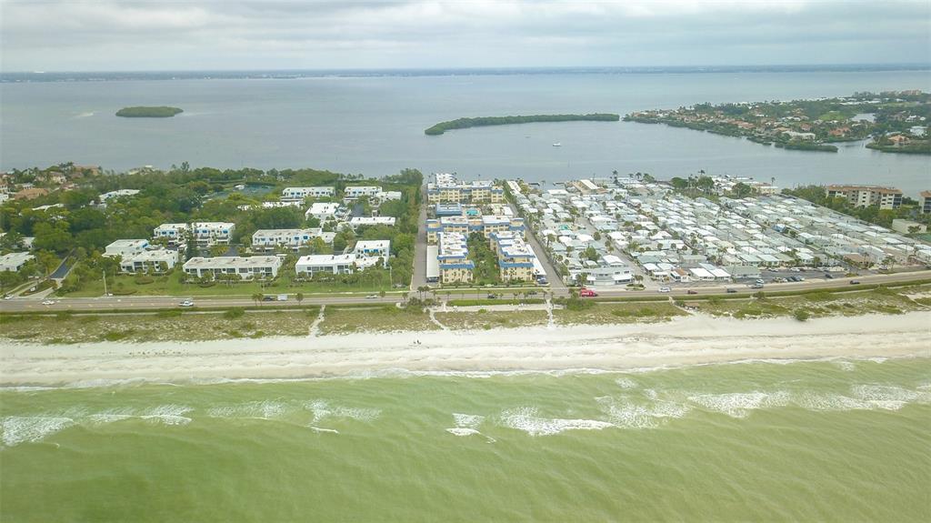 An aerial view shows a beach, a coastal road, and residential buildings along the water — 3804 GULF OF MEXICO DRIVE UNIT B307, LONGBOAT KEY, FL