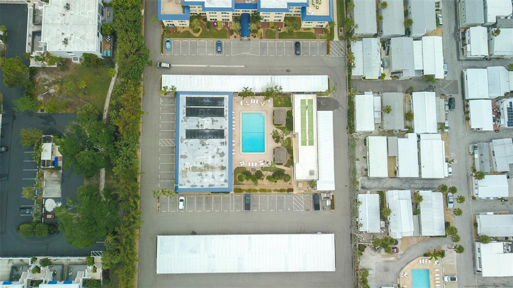 An aerial view shows a residential complex with a swimming pool, parking lots, and buildings — 3804 GULF OF MEXICO DRIVE UNIT B307, LONGBOAT KEY, FL