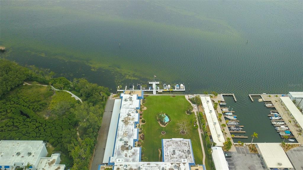 An aerial view shows a waterfront apartment complex with a central lawn and boat docks — 3804 GULF OF MEXICO DRIVE UNIT B307, LONGBOAT KEY, FL