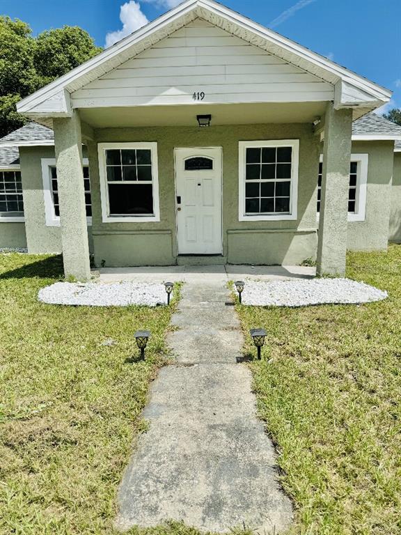 A front view of a single-story house with a covered porch and white trim — 419 AVENUE M NE, WINTER HAVEN, FL