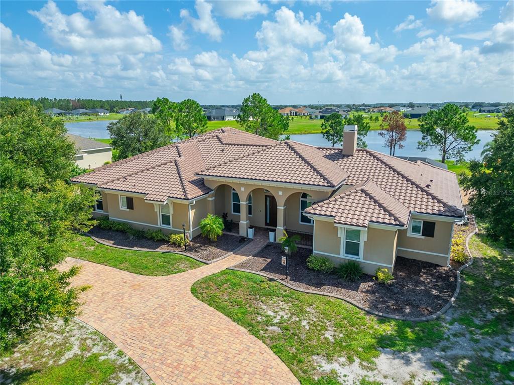 An aerial view of a tan, single-story house with a tiled roof and brick driveway — 5207 LAKE VENICE DRIVE, WIMAUMA, FL