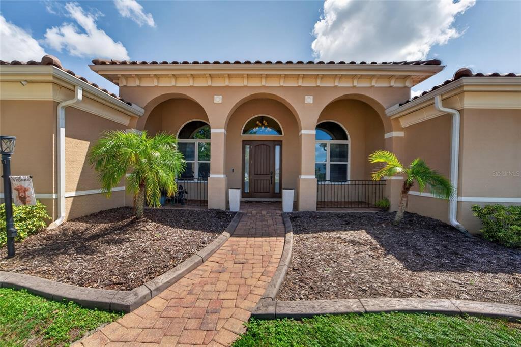 A tan stucco house with a tiled roof, arched entryway, and a brick walkway — 5207 LAKE VENICE DRIVE, WIMAUMA, FL