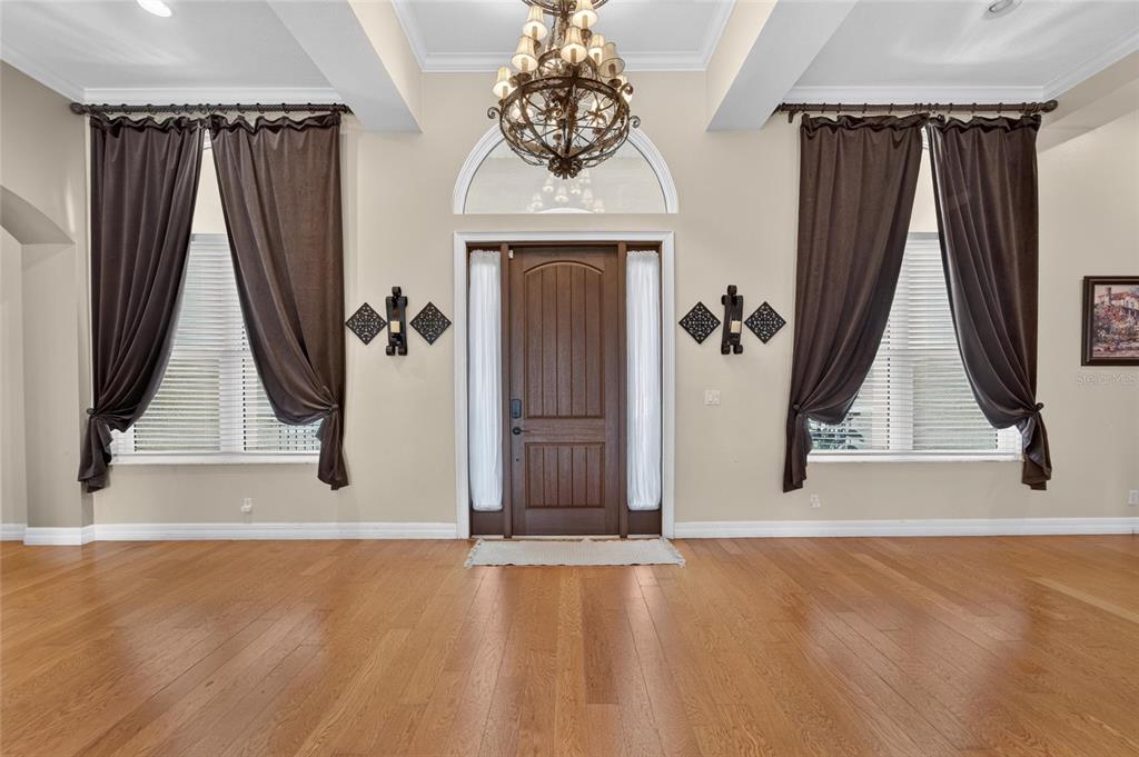 A foyer with hardwood floors, a wooden front door, and dark curtains over windows — 5207 LAKE VENICE DRIVE, WIMAUMA, FL