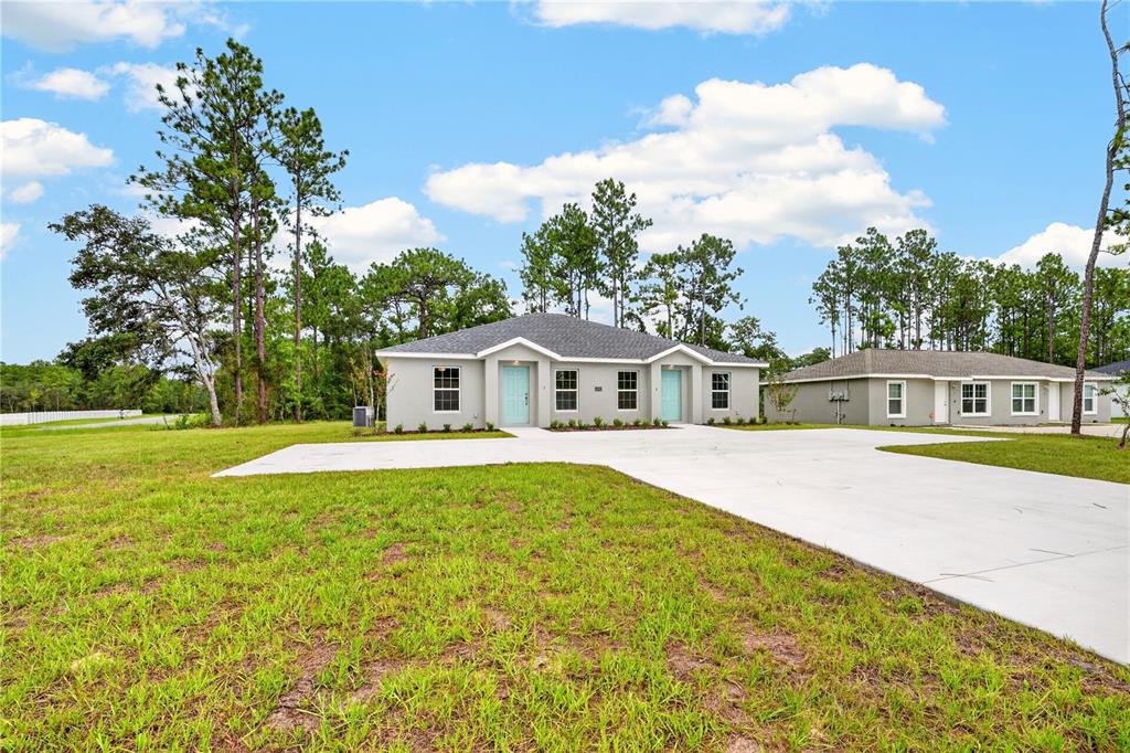 A duplex with light gray siding and two light blue front doors sits on grass — 14001 SW 60TH TERRACE, OCALA, FL