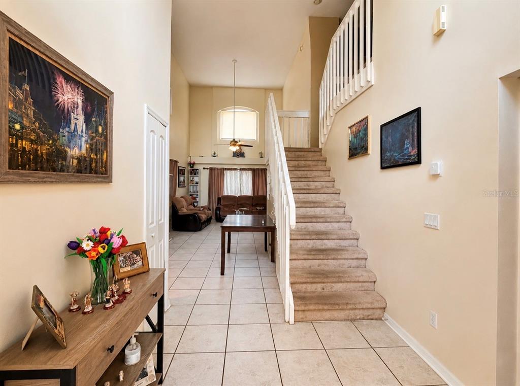 A tiled entryway leads to a carpeted staircase and a living area with high ceilings — 2728 EMERSON LANE, KISSIMMEE, FL