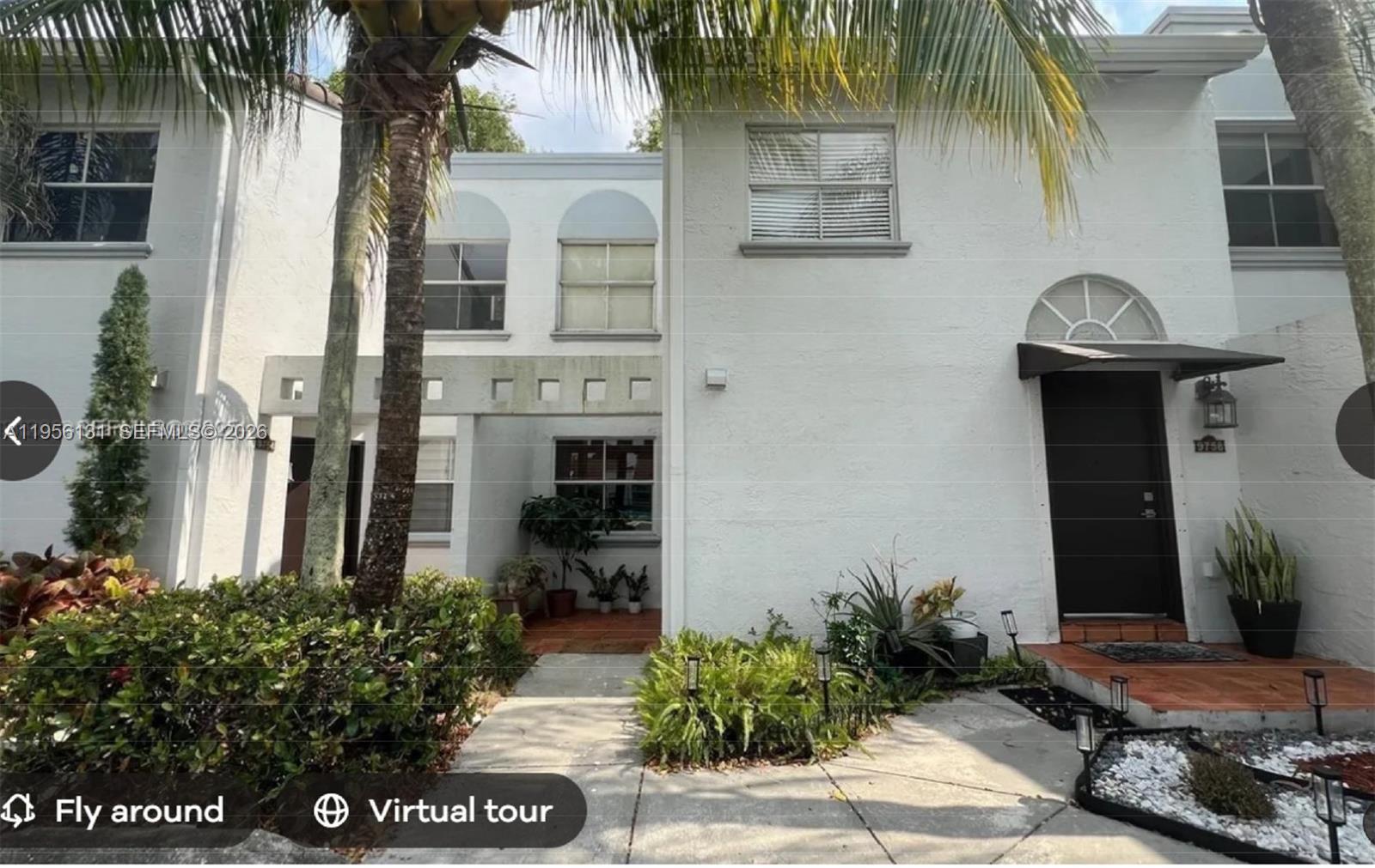 A white two-story townhouse exterior features a dark front door and a paved walkway — 4654 NW 97th Ct # 95, Doral FL 33178, DORAL, FL