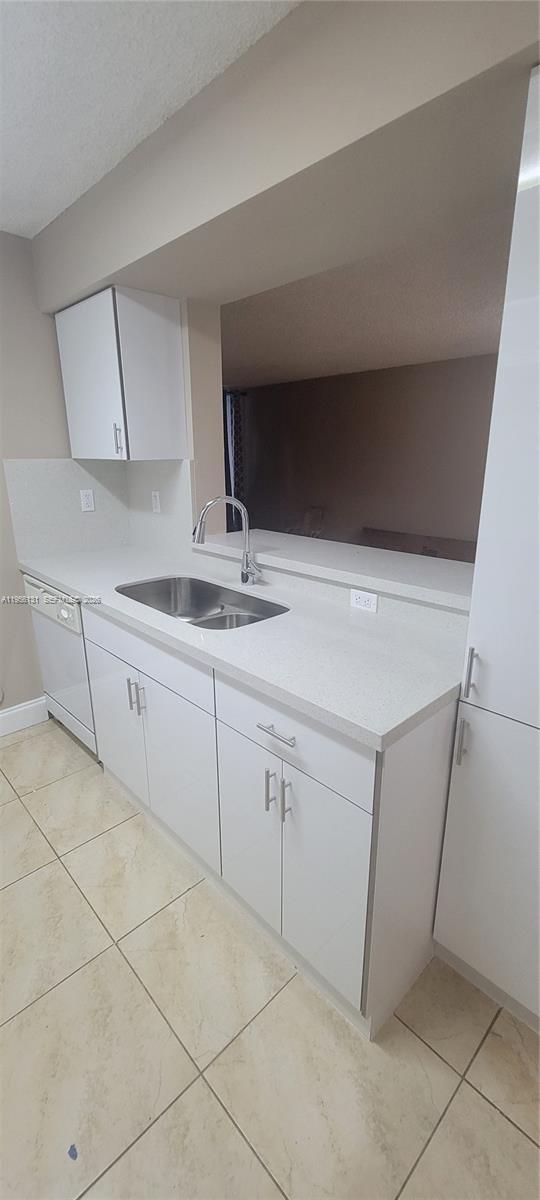 A kitchen features white cabinets, a stainless steel sink, and light-colored tile flooring — 4654 NW 97th Ct # 95, Doral FL 33178, DORAL, FL