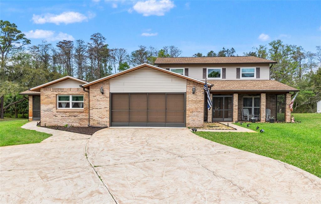 A two-story brick and siding house features a large garage and a covered front porch — 1357 DINSMORE COURT, NEW PORT RICHEY, FL